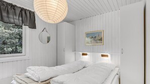A bedroom with a bed, a mirror, a painting, and a window with curtains. - Nice home in Aakirkeby with WiFi (Aakirkeby)
