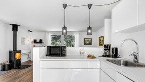 A modern kitchen with white cabinetry, a built-in stove, a microwave, and a coffee maker. - Nice home in Aakirkeby with WiFi (Aakirkeby)