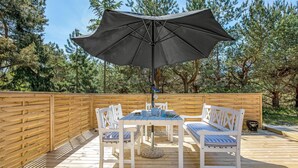 A wooden deck with a table and chairs, an umbrella, and a wooden fence. - Nice home in Aakirkeby with WiFi (Aakirkeby)