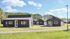 Een rij kleine, donkerkleurige hutten, met een picknicktafel voor de eerste hut.