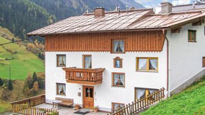 Eine zweistöckige Chalet mit Holzbalkon, zahlreichen Fenstern und Blick auf eine Berglandschaft.