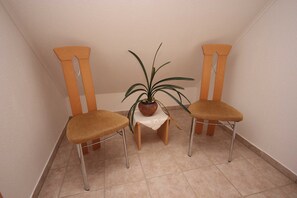 Deux chaises en bois avec des pieds en métal, une petite table sur laquelle est posée une plante en pot et un sol carrelé.