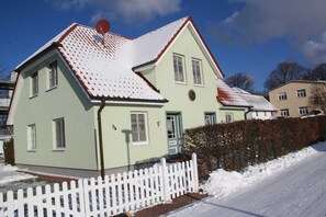 Et toetagers hus med hvid stakittet hegn, rødt tag og en parabol.
