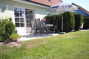 Un patio con una mesa y sillas, un paraguas a rayas y una planta en maceta.