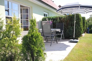A patio with a chair, a table, and an umbrella. - By the Sea, Port Side - By the Sea - Port Side (Wustrow)