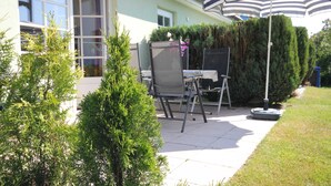 A patio with a chair, a table, and an umbrella. - By the Sea, Port Side - By the Sea - Port Side (Wustrow)