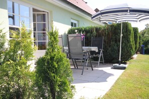 Un patio con una silla, una mesa y una sombrilla.