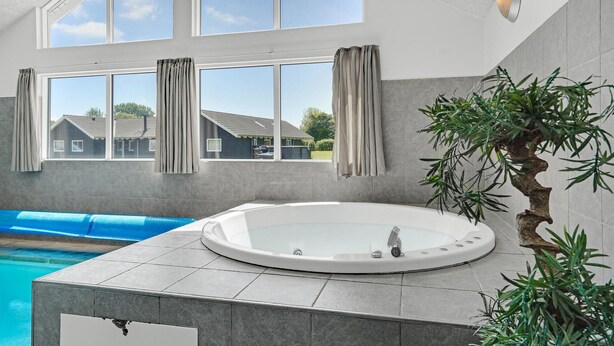 A modern bathroom with a glass-enclosed hot tub, large windows, and a view of a residential area. - Nice home in Sydals with sauna (Sydals)