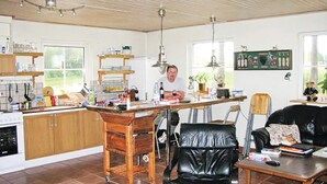A kitchen with a wooden island, a dining area with a leather chair, and a black leather sofa. - Amazing home in Ljungsarp with sauna (Ljungsarp)