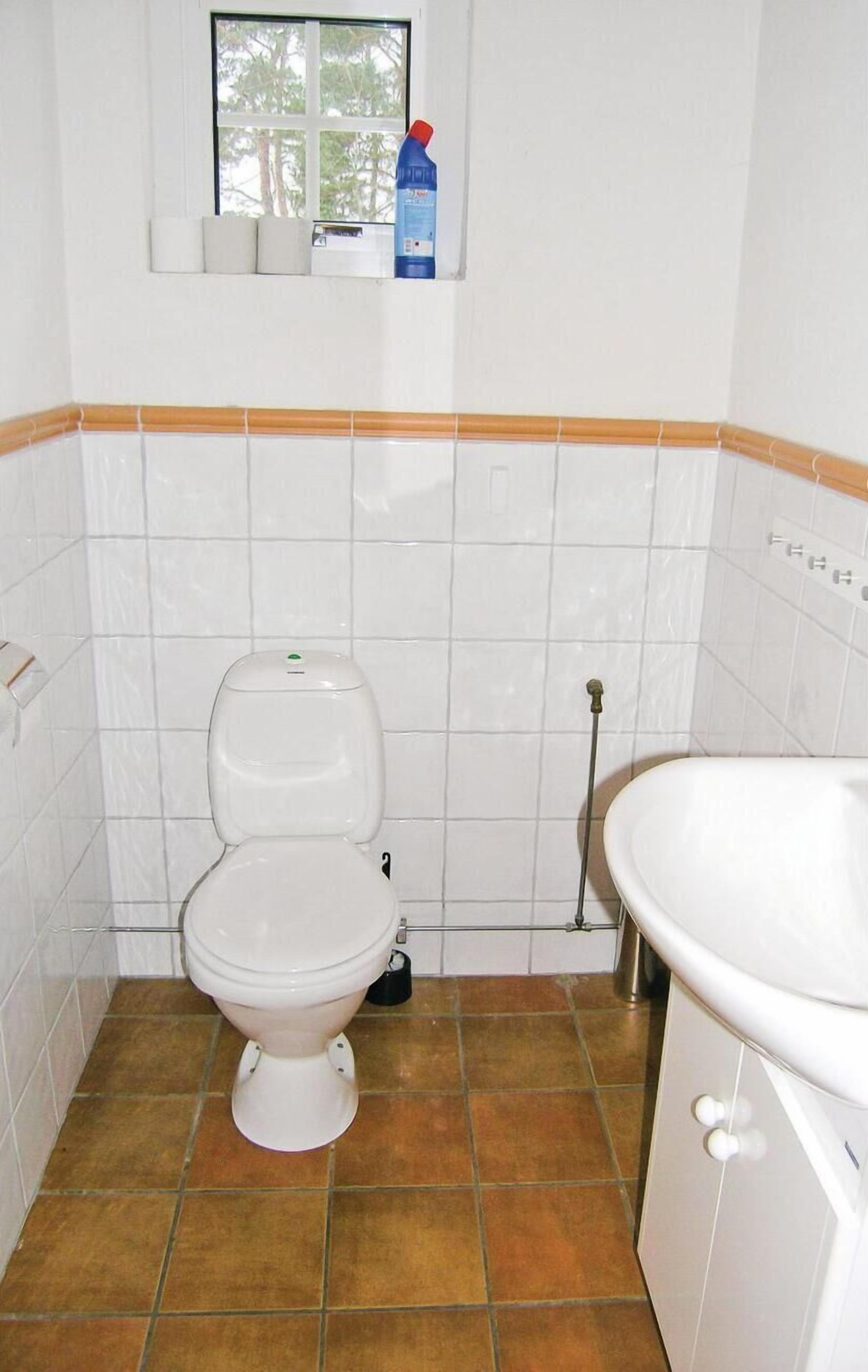 A small bathroom with a toilet, a sink, and a window above the toilet.