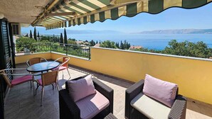 A balcony with wicker furniture, a view of the sea, and a clear sky.