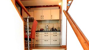 A staircase leading to a kitchen with white cabinets and wooden steps. - Holiday apartment with a view of the Franconian Forest (Blankenstein)