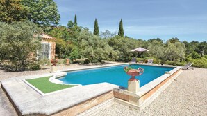 A rectangular swimming pool with a stone border, surrounded by a gravel area. There are lounge chairs and a small table with an umbrella. - Beautiful home in Les Baux de Provence (Les Baux de Provence)