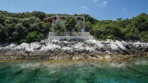 A stone building with a staircase leading up to it, surrounded by rocky terrain and trees. - Beach front home in Osobjava with house sea view (Osobjava)