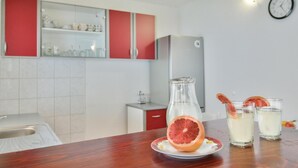 A kitchen with a wooden table, a red cabinet, and a clock on the wall. - Beach front home in Osobjava with house sea view (Osobjava)