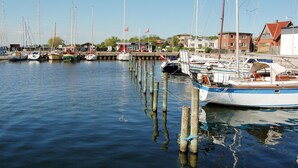 A marina with multiple boats docked, wooden pilings, and buildings in the background. - Amazing home in Askeby with kitchen (Askeby)