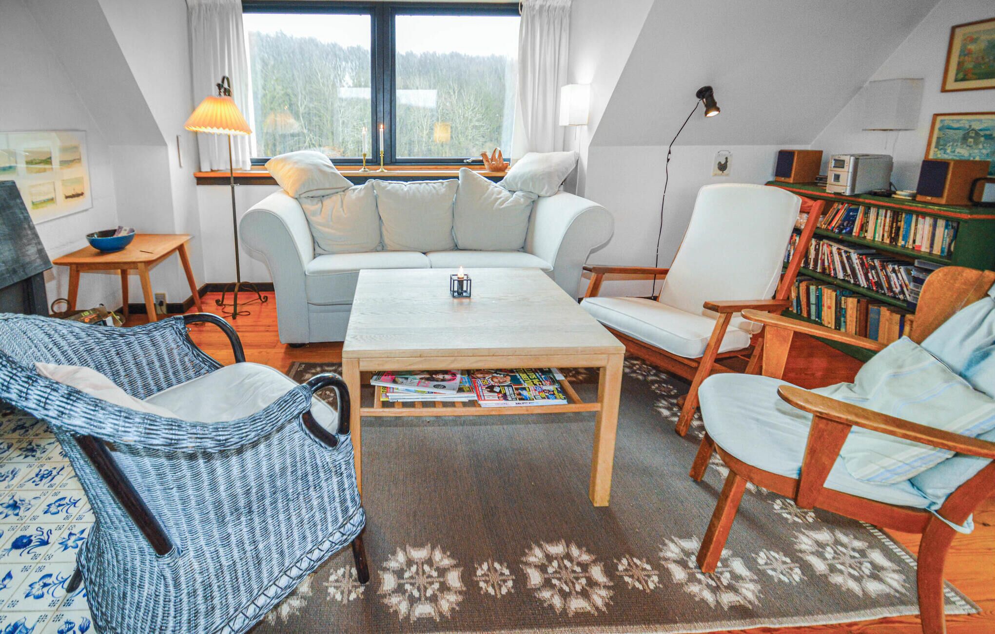 A cozy living room with a sofa, armchairs, a coffee table, and a bookshelf.