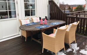 A wooden deck with a round table and four wicker chairs, a wooden railing, and a snowy ground. - Gorgeous home in Mollösund with kitchen (Mollösund)