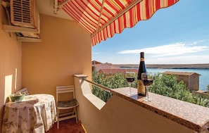 Enjoy a serene view of the water and distant hills from this balcony, complete with a table and chair.