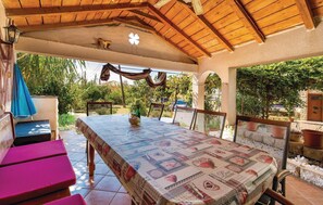 Enjoy al fresco dining under a covered roof with a view of lush surroundings.