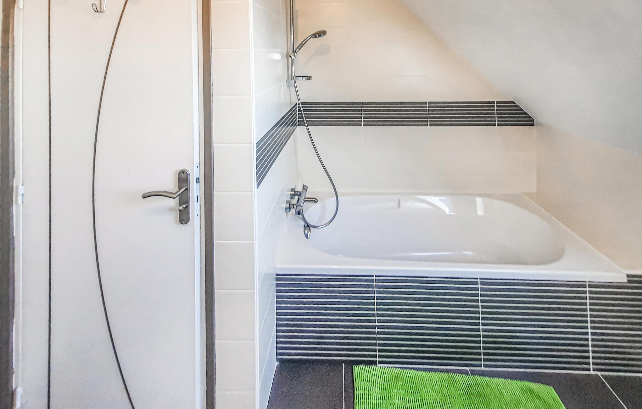 Une salle de bain avec une baignoire, une douche et une porte.