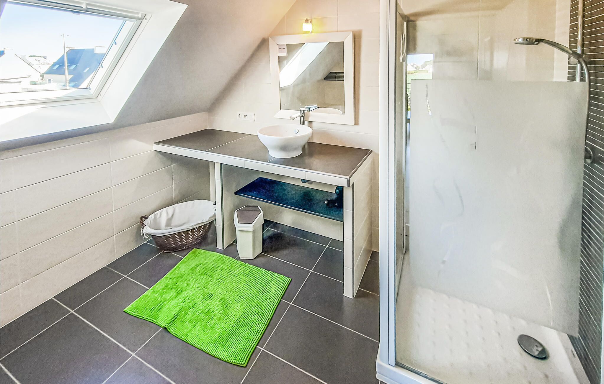 Un baño moderno con tragaluz, un espejo grande, un lavabo y una ducha.