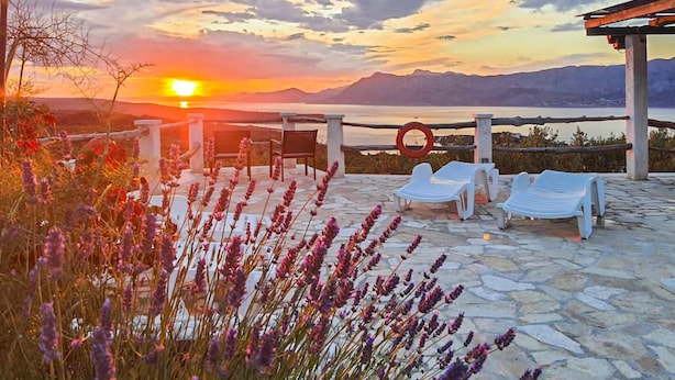 A sunset view from a terrace with stone flooring, white lounge chairs, and a pergola. - Gorgeous home in Povlja (Povlja)