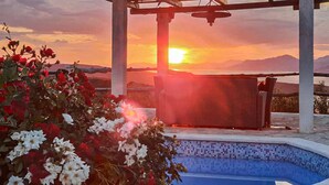 A pool area with a pergola, a bench, and a view of the sunset over mountains. - Gorgeous home in Povlja (Povlja)