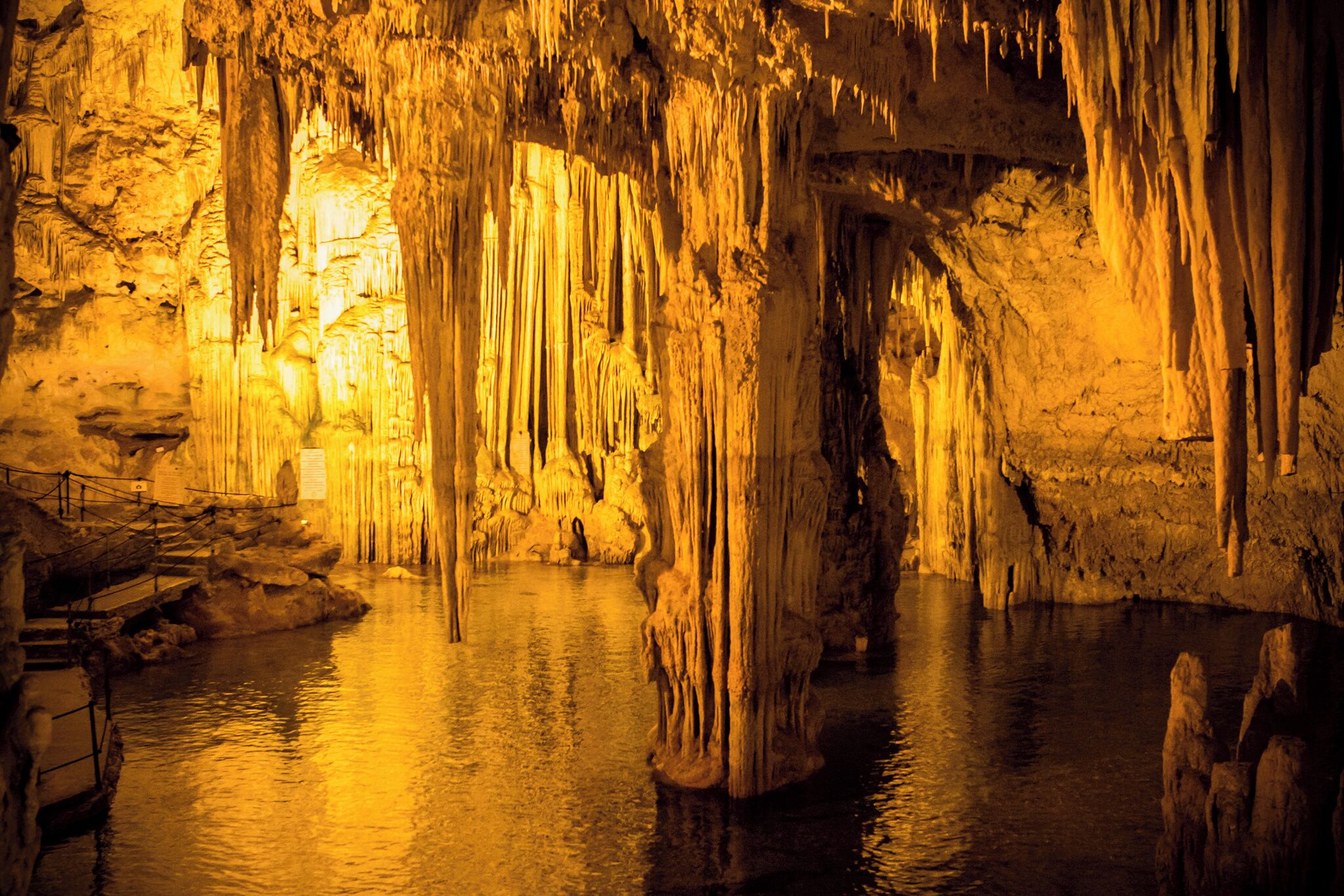 En hule med stalaktitter og stalagmitter, et vandareal og en trappe.