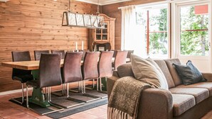 A dining area with a wooden table and chairs, a sofa with cushions, and a window with curtains. - Stunning home in Trysil with sauna (Trysil)