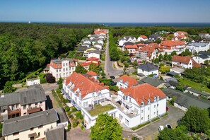 A residential area with houses featuring red roofs, a central road, and a view of the sea in the background. - Am Stadtwald Apartment 3 - Am Stadtwald Strandstr. 15, WE 3 (Kühlungsborn)