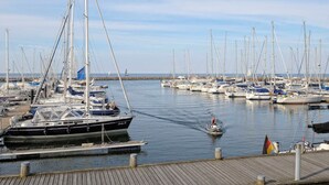 Un port de plaisance où sont amarrés plusieurs voiliers, une personne sur un jet ski et une jetée en bois.
