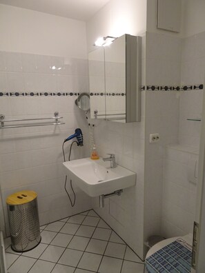 A bathroom with a white sink, mirror, and tiled walls. - Am Stadtwald Apartment 3 - Am Stadtwald Strandstr. 15, WE 3 (Kühlungsborn)