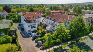 Un quartier résidentiel avec des maisons, un grand immeuble blanc doté d’un balcon et une rue.