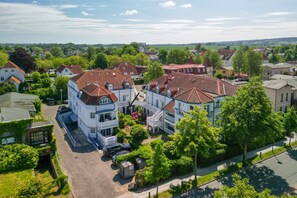 Un quartier résidentiel avec des maisons, un grand immeuble blanc doté d’un balcon et une rue.