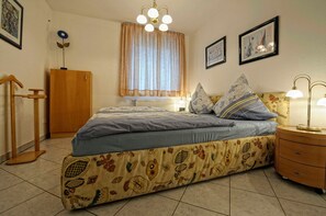 A bedroom with a bed, bedside table, lamp, curtains, and a radiator. - Am Stadtwald Apartment 3 - Am Stadtwald Strandstr. 15, WE 3 (Kühlungsborn)