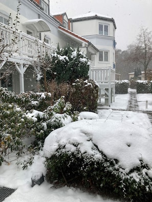 Een besneeuwde woonwijk met huizen, een pad en een witte hek.