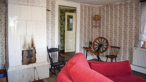 Ein Zimmer mit einem roten Sofa, einem hölzernen Spinnrad und einem Sessel.