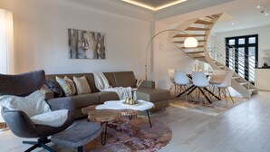 En moderne stue med sofa, lænestol, sofabord og en unik spiraltrappe.