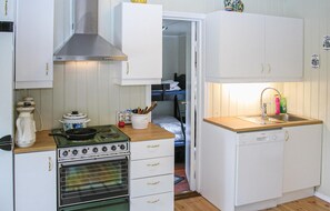 Eine kompakte Küche mit Herd, Backofen und Spüle. Es gibt Schränke und eine kleine Arbeitsplatte.