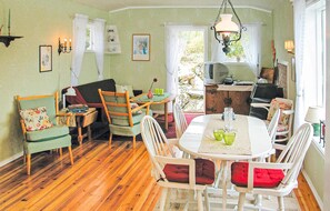 Un coin repas chaleureux avec un plancher en bois, une table ronde et des chaises blanches.
