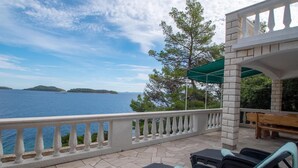 A balcony with a view of the sea, outdoor furniture, and a stone building. - Beautiful home in Prizba with kitchen (Prizba)