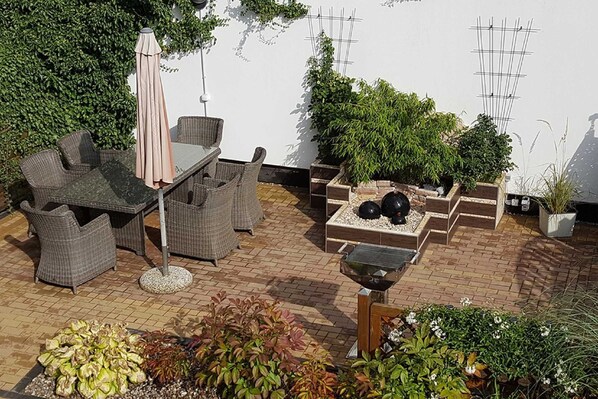 A patio with wicker furniture, a table, and a potted plant arrangement.