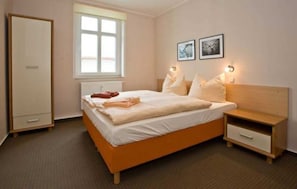 Une chambre à coucher avec un lit, des tables de chevet, une armoire et une fenêtre.