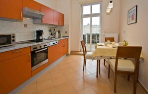 Une cuisine avec des meubles de couleur orange, une cuisinière et un coin repas comprenant une table et des chaises.