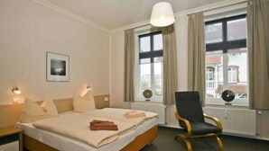 A hotel room with a bed, bedside tables, a chair, and a window with curtains. - Apartment I - Villa Elfriede (Sassnitz)