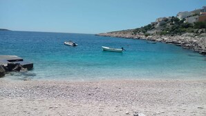 Ein Kiesstrand mit Booten und felsigem Gelände.