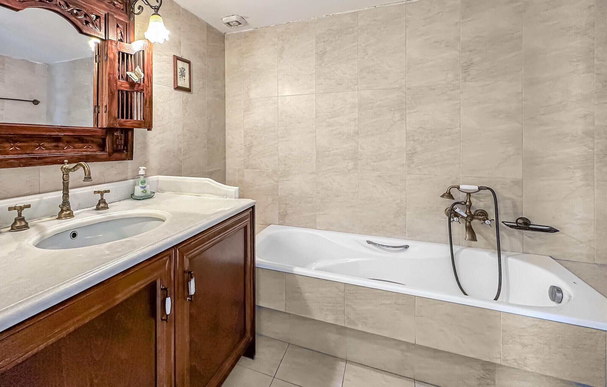 Un baño con lavamanos doble, bañera y armario de madera.