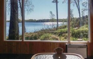A room with a large window overlooking a lake, a radiator, and a small table with a decorative item. - Lovely home in Skånes Fagerhult (Skånes Fagerhult)