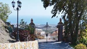 Eine Steinsäule, ein Metallgitter und der Blick auf eine Stadtlandschaft.